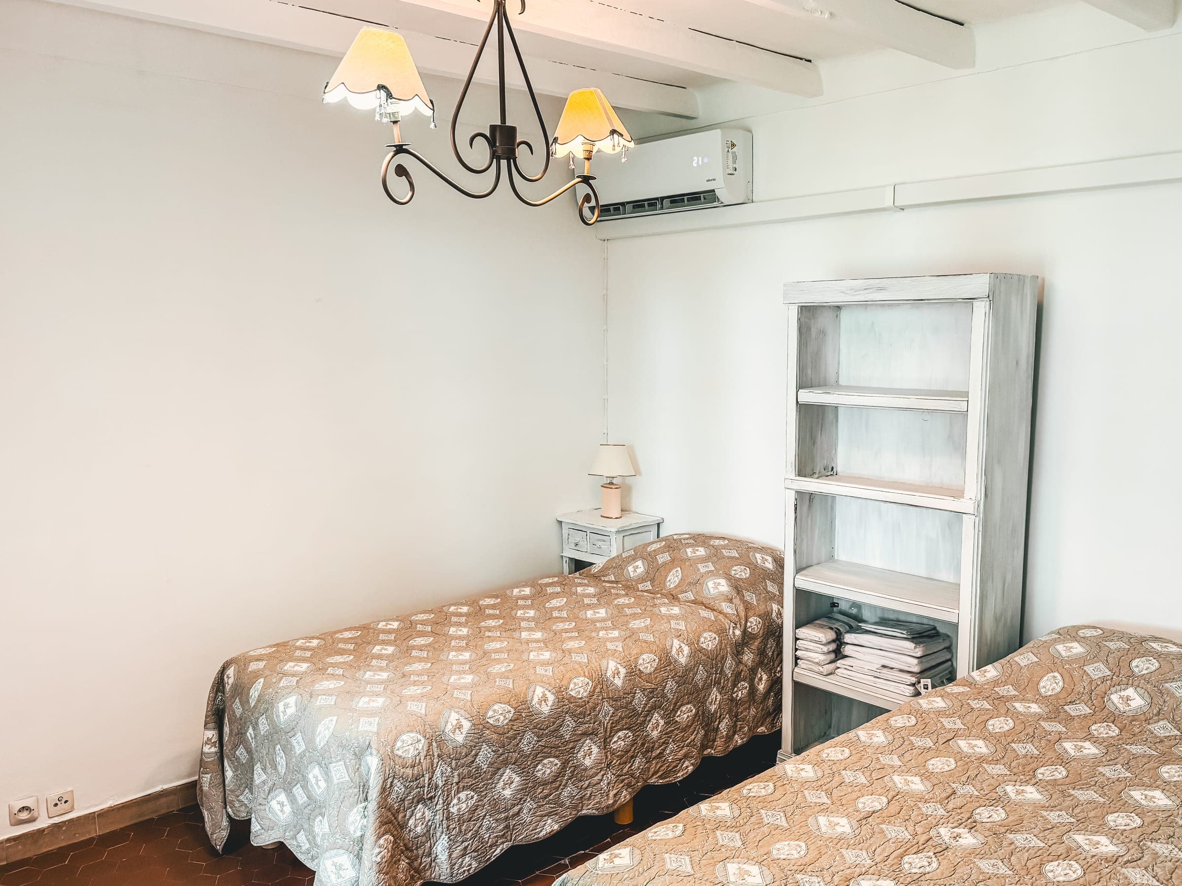 Chambre lumineuse avec couvre-lits à motifs et étagères blanches
