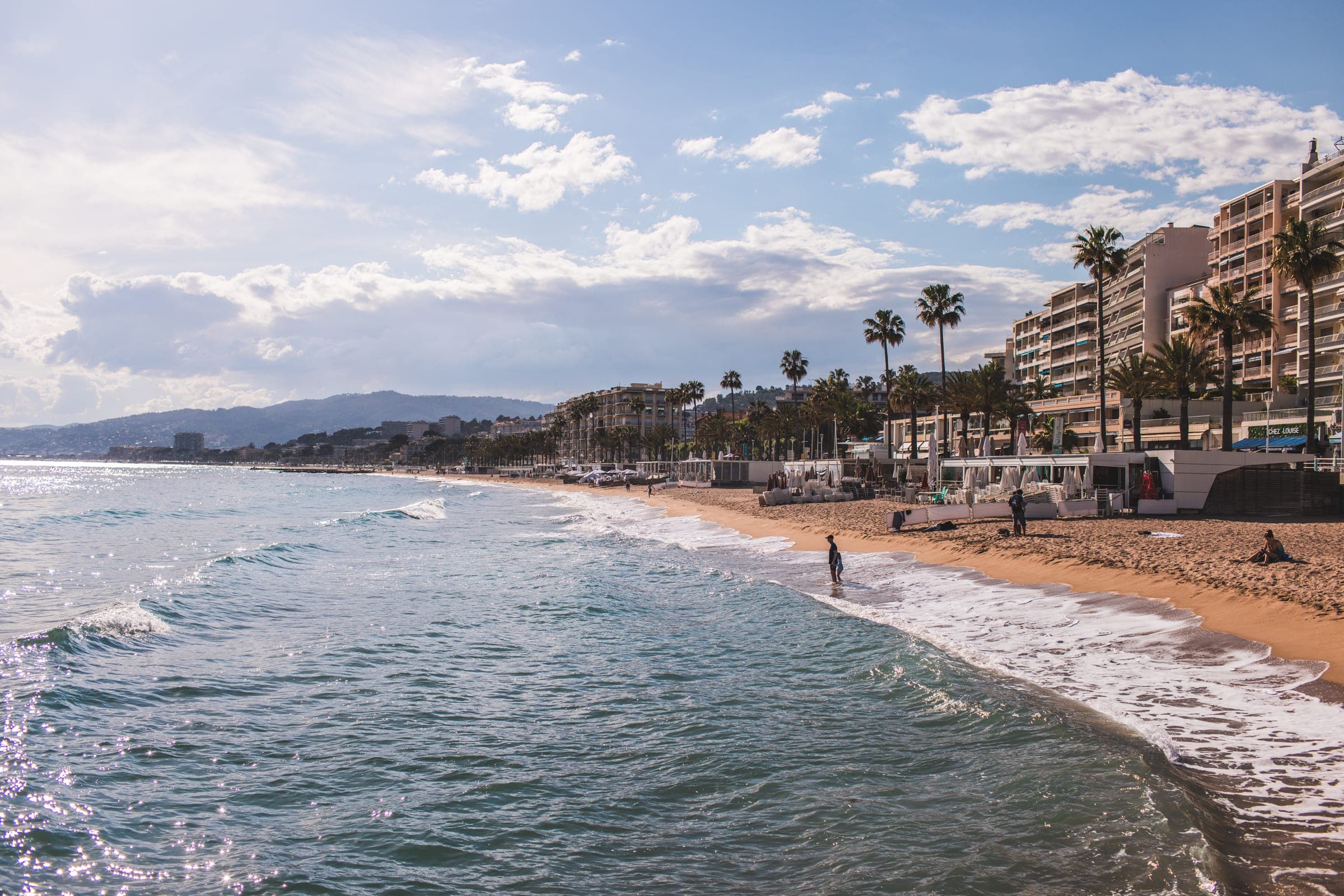 Vagues sur une plage de la Côte d’Azur bordée de palmiers