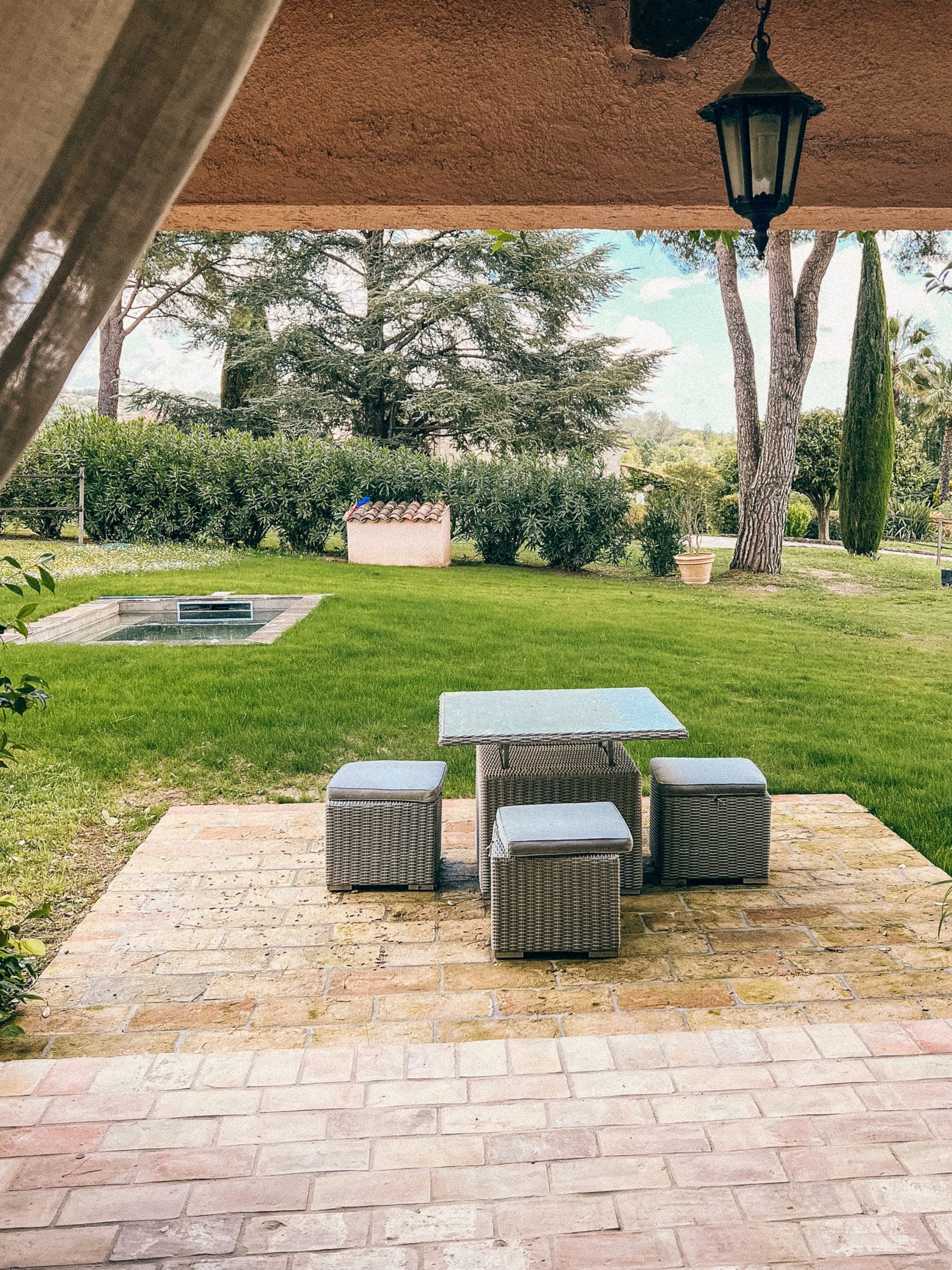 Coin salon ombragé avec table sur la terrasse, face au jardin