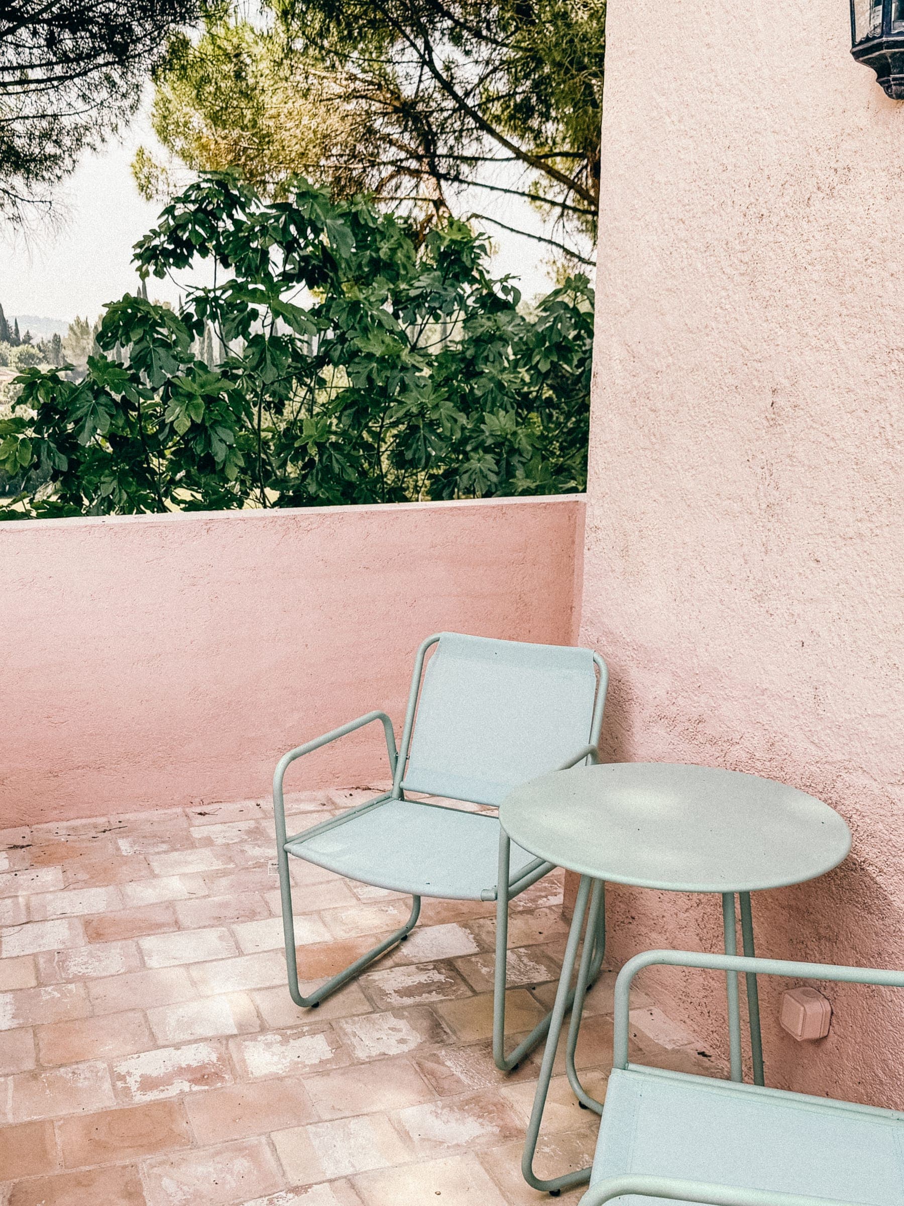 Terrasse privée aux murs roses, carreaux de terre cuite, table et chaises